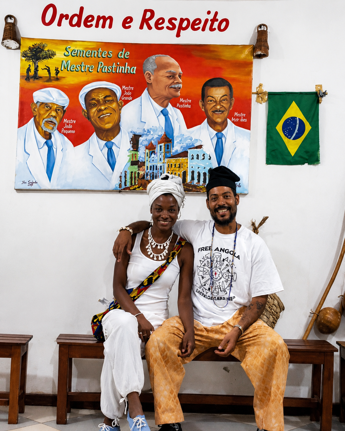 Practitioners seated beneath a mural honoring Mestre Pastinha, Mestre João Grande, Mestre João Pequeno and Mestre Moraes