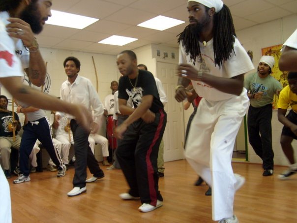 Adults and youth training capoeira movements together in class