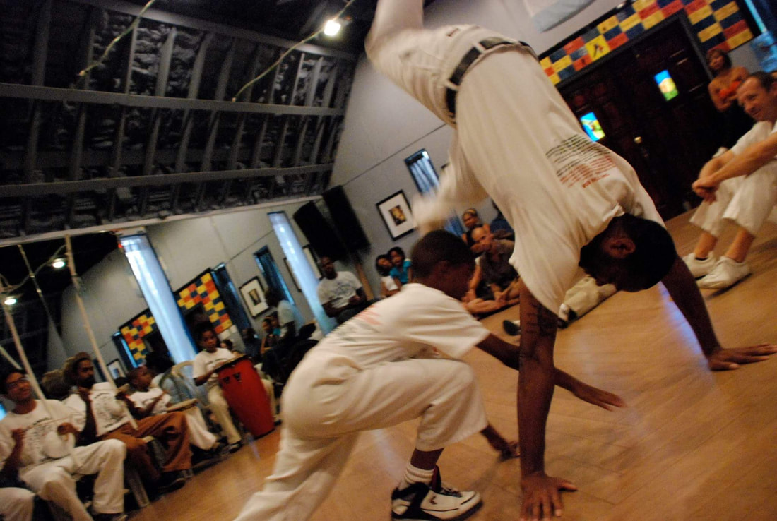 Two students playing low inside an indoor roda