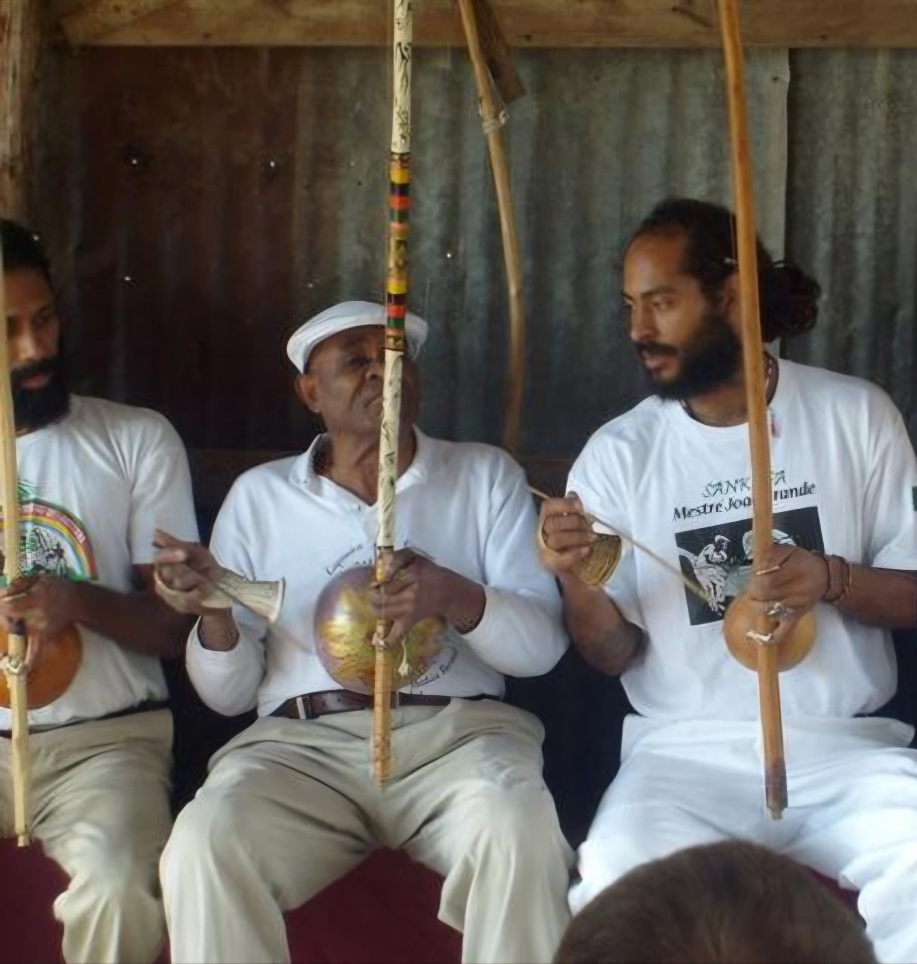 An elder mestre and students playing berimbaus together